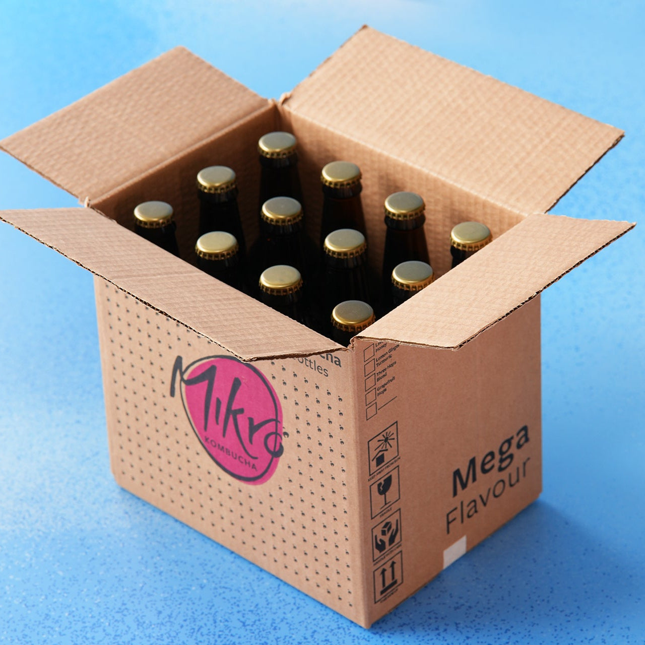 Cardboard box labelled Mikro kombucha with 12 bottles on a blue background