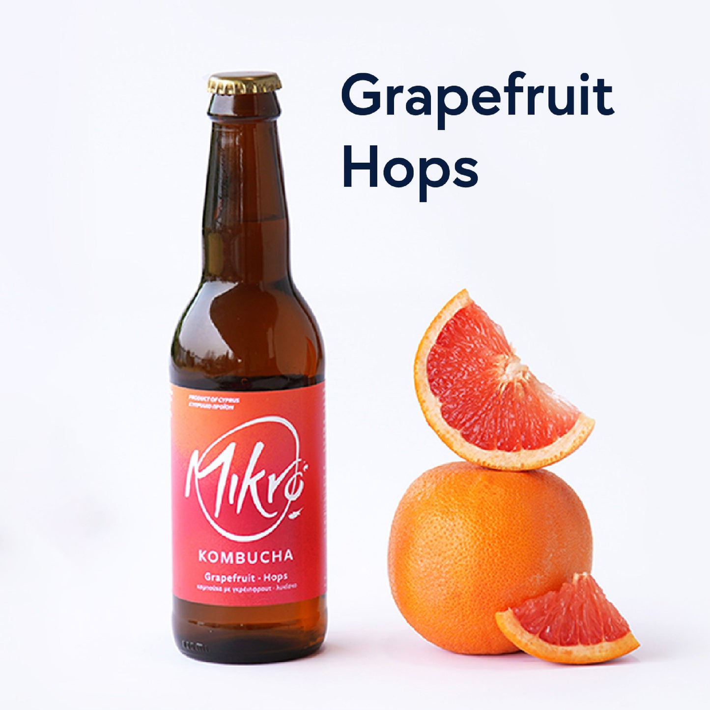 Mikro Grapefruit Hops Kombucha bottle with red and orange label next to grapefruit wedges on a white background