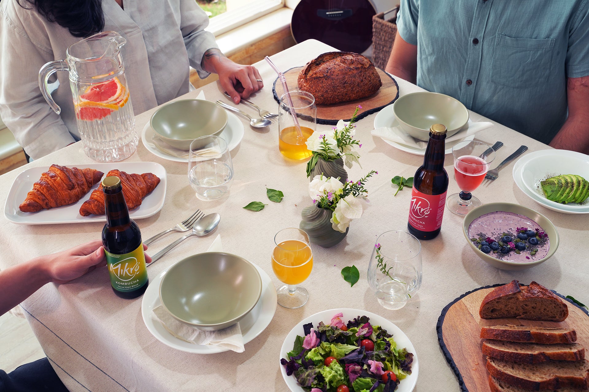 People sitting around a table with food and Mikro kombucha bottles