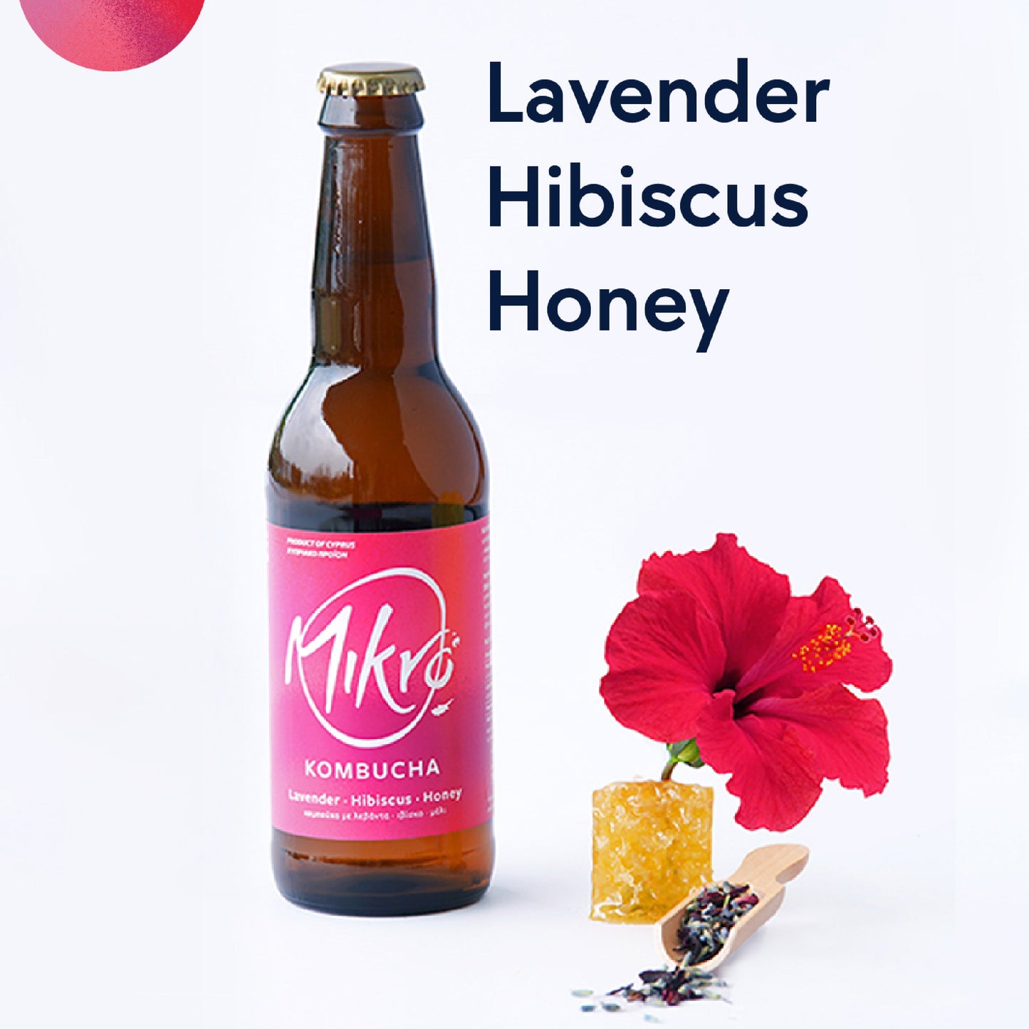 Mikro Lavender Hibiscus Honey Kombucha bottle with bright pink and purple label next to lavender buds, hibiscus flower and honey comb piece on a white background