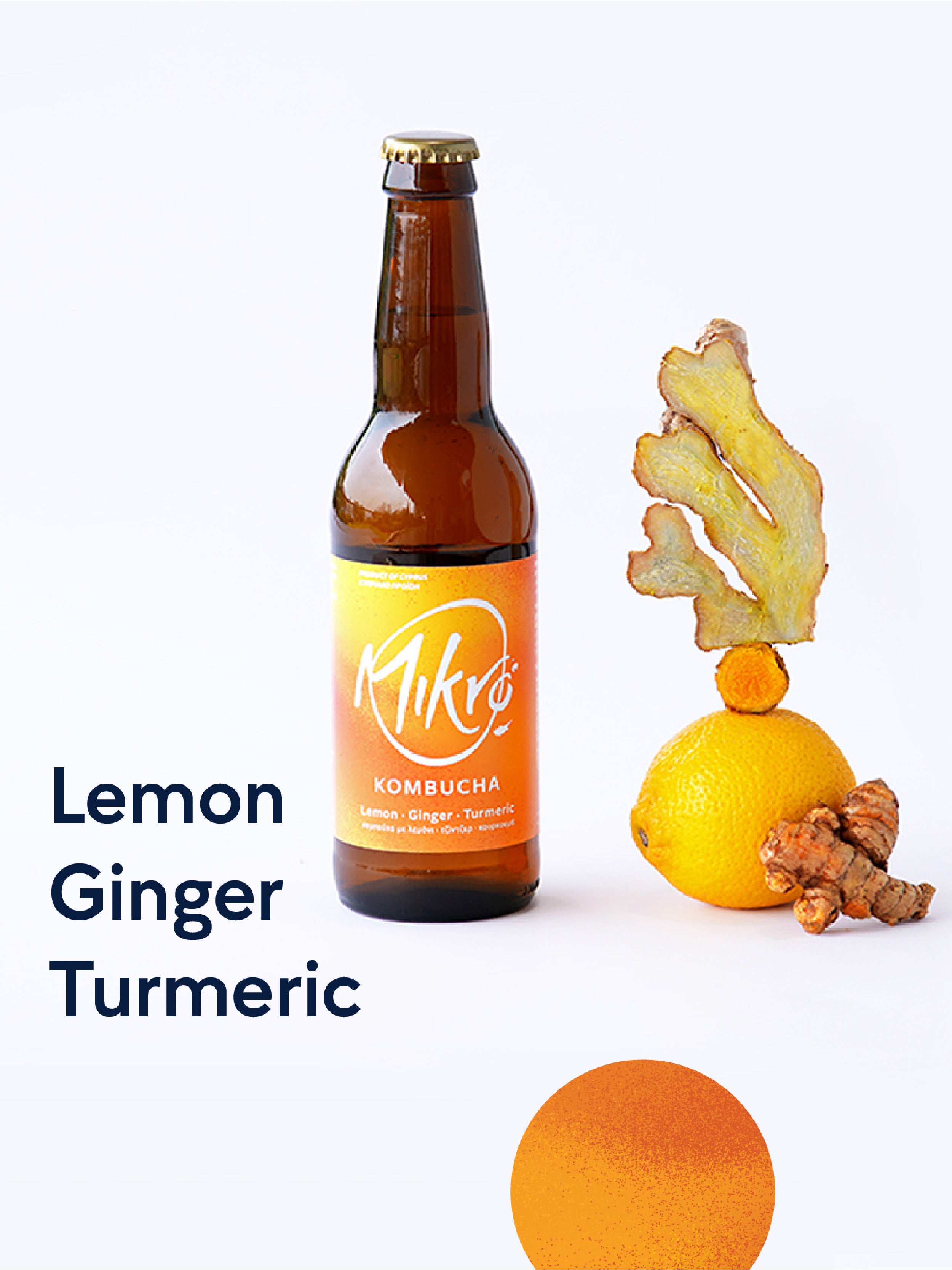 Mikro Lemon Ginger Turmeric kombucha bottle with bright yellow label next to a lemon, ginger, and turmeric pieces on a white background.