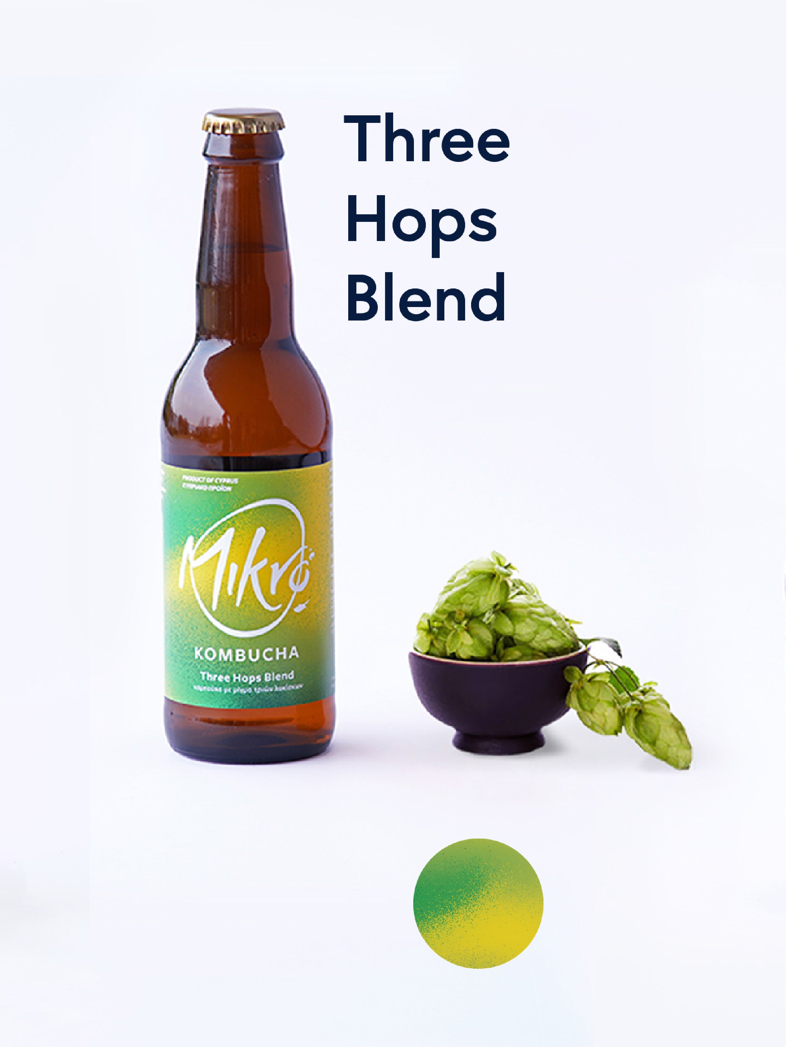 Mikro Three Hops bled kombucha bottle with bgright green and yellow label next to a bowl of hops buds on a white background